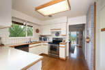 This charming kitchen features white cabinetry, a tiled backsplash, and a stainless steel range.