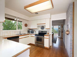 This charming kitchen features white cabinetry, a tiled backsplash, and a stainless steel range.