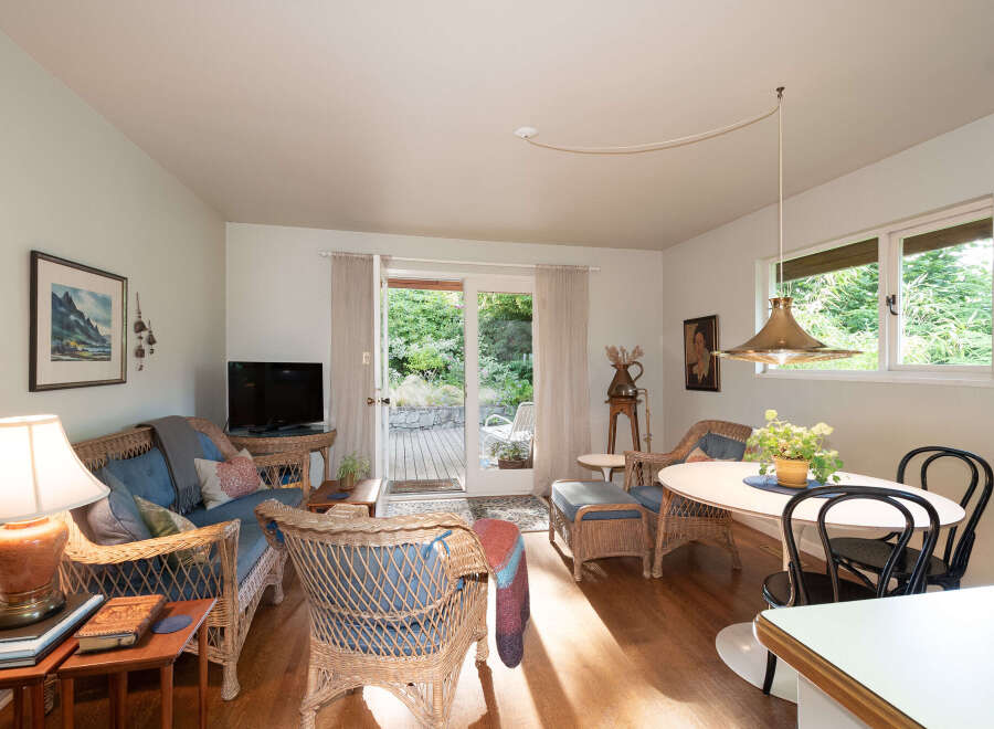 Step into this charming living and dining area, featuring a cozy wicker sofa and chairs perfect for relaxation.