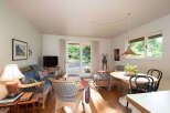 Step into this charming living and dining area, featuring a cozy wicker sofa and chairs perfect for relaxation.