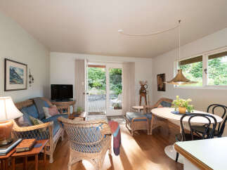 Step into this charming living and dining area, featuring a cozy wicker sofa and chairs perfect for relaxation.