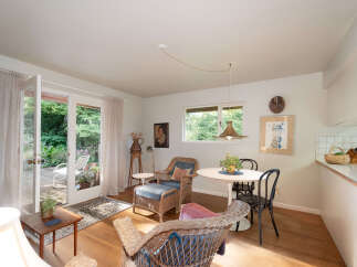 Step into this charming living space featuring a cozy seating area with wicker chairs and a dining nook perfect for intimate meals.