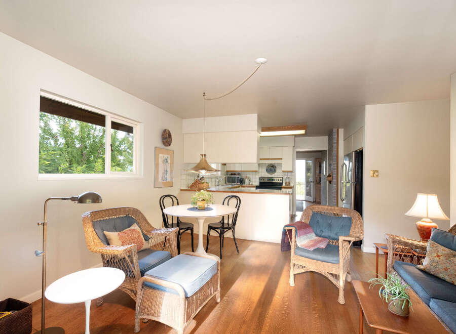 This charming living and dining area features a cozy wicker seating arrangement with plush blue cushions, perfect for relaxing.