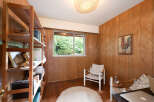 This cozy room features warm wood paneling and a large window offering a lush green view.