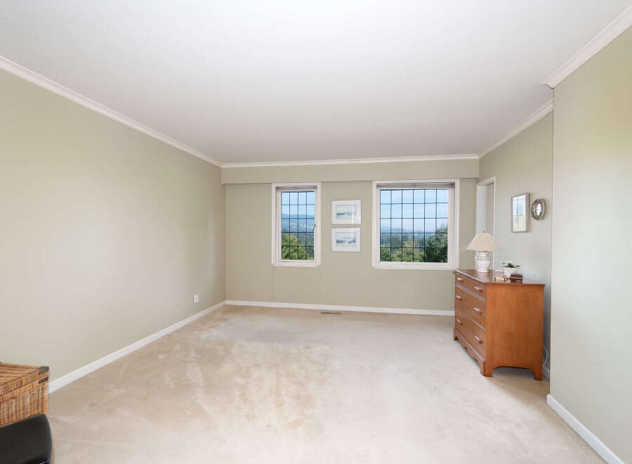 Experience breathtaking views from this spacious bedroom, featuring large windows that showcase a lush, green landscape.