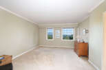 Experience breathtaking views from this spacious bedroom, featuring large windows that showcase a lush, green landscape.