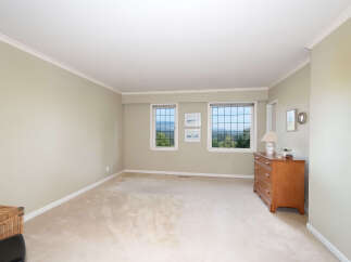 Experience breathtaking views from this spacious bedroom, featuring large windows that showcase a lush, green landscape.