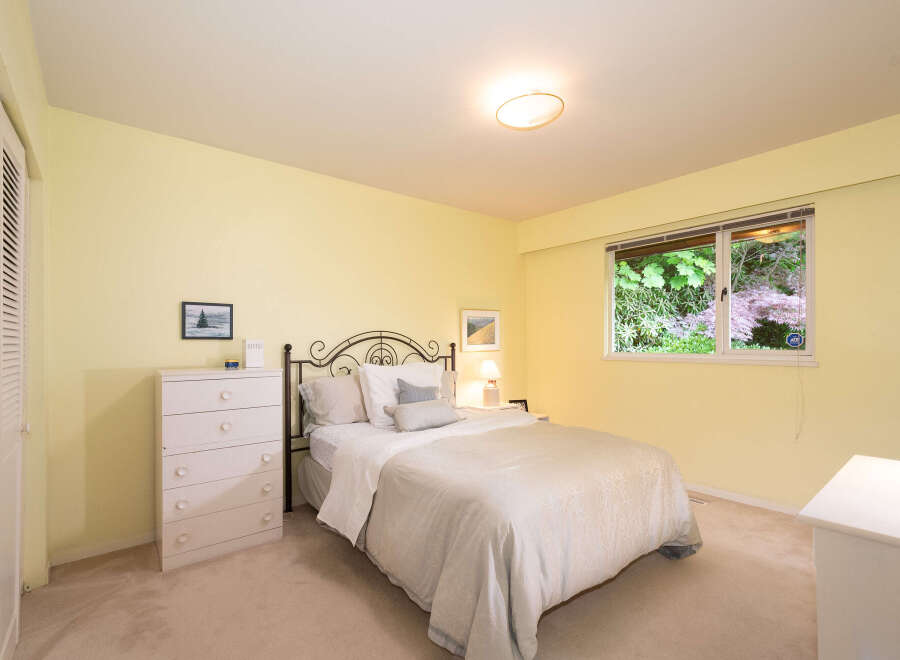 Discover comfort and style in this charming bedroom, featuring a cozy queen-size bed with a decorative metal headboard and a light-colored duvet.