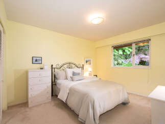 Discover comfort and style in this charming bedroom, featuring a cozy queen-size bed with a decorative metal headboard and a light-colored duvet.