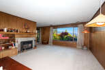 Experience breathtaking mountain and valley views from this spacious living room, featuring a cozy fireplace and ample natural light.