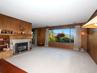 Experience breathtaking mountain and valley views from this spacious living room, featuring a cozy fireplace and ample natural light.