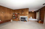 Step into this charming living room featuring warm wood-paneled walls and a cozy fireplace, perfect for gathering.
