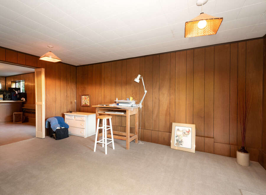 Discover a versatile space with this room, featuring warm wood paneling and a comfortable carpeted floor.