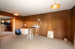 Discover a versatile space with this room, featuring warm wood paneling and a comfortable carpeted floor.