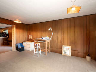 Discover a versatile space with this room, featuring warm wood paneling and a comfortable carpeted floor.