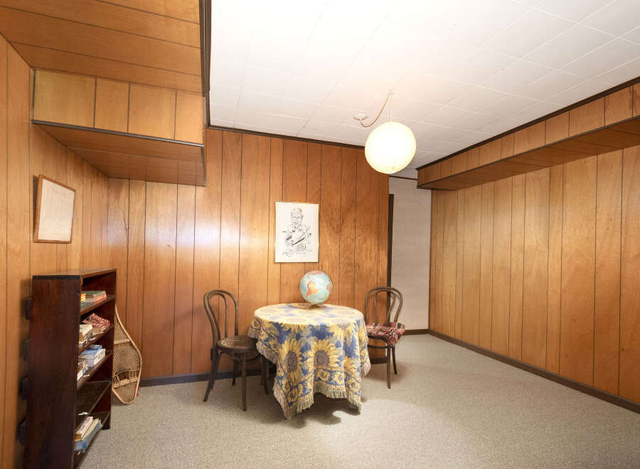 Step into a retro-inspired living space featuring warm wood paneling throughout, creating a cozy and inviting atmosphere.