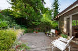 Enjoy outdoor living on this charming wooden deck, surrounded by lush greenery and mature trees.