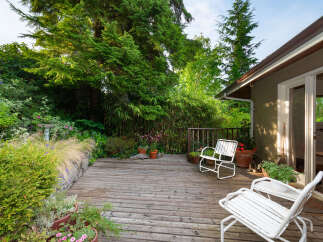 Enjoy outdoor living on this charming wooden deck, surrounded by lush greenery and mature trees.