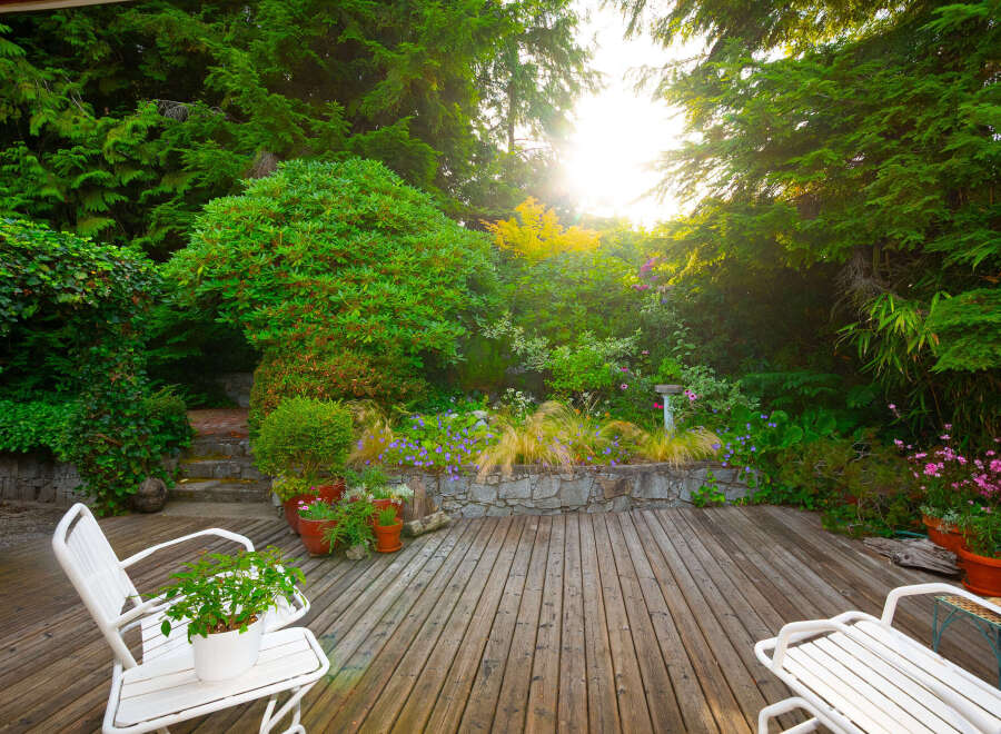 Enjoy serene outdoor living on this charming wooden deck, surrounded by lush greenery and vibrant flowers.