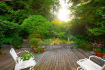 Enjoy serene outdoor living on this charming wooden deck, surrounded by lush greenery and vibrant flowers.