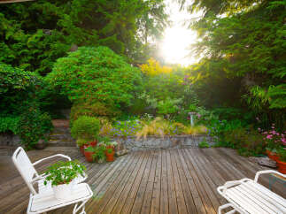 Enjoy serene outdoor living on this charming wooden deck, surrounded by lush greenery and vibrant flowers.
