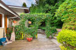 Step into a lush backyard oasis featuring a charming ivy-covered archway leading to a serene seating area.