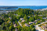 Discover this stunning aerial view of a lush, green neighborhood nestled on a hillside overlooking the water.