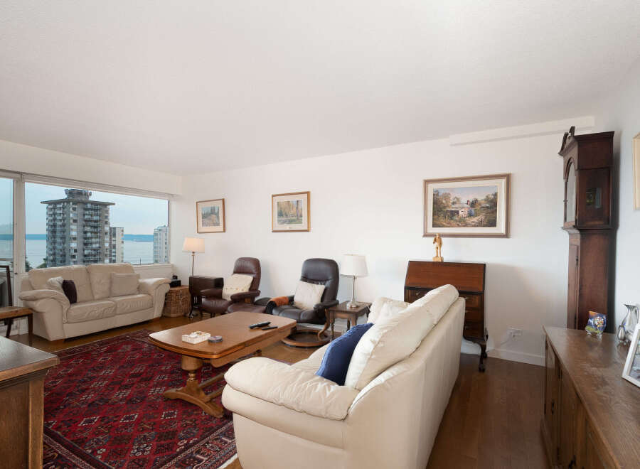 Experience breathtaking water and city views from this spacious living room, featuring a large window overlooking the cityscape.