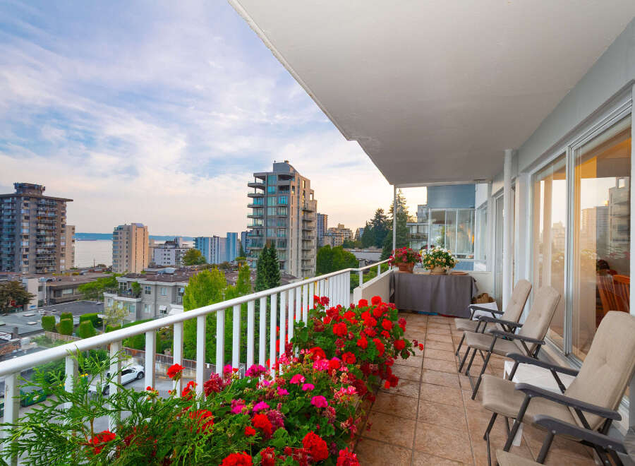 Enjoy breathtaking city and water views from this stunning balcony, adorned with vibrant red and pink flowers.