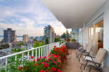 Enjoy breathtaking city and water views from this stunning balcony, adorned with vibrant red and pink flowers.