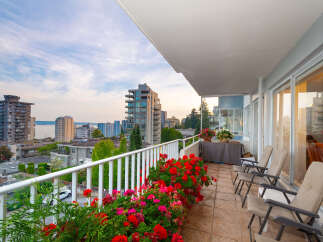 Enjoy breathtaking city and water views from this stunning balcony, adorned with vibrant red and pink flowers.