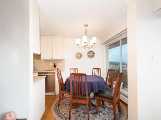 Enjoy meals with loved ones in this charming dining area, featuring a round table draped in a deep blue tablecloth and surrounded by classic wooden chairs.