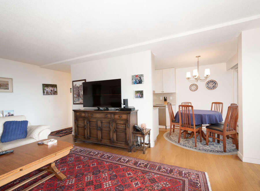 This inviting living and dining area features a comfortable white sofa adorned with a blue throw pillow, perfect for relaxing.