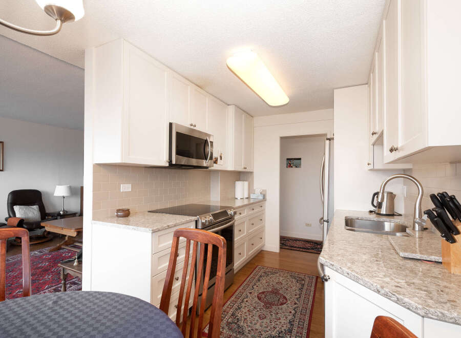 This bright and airy kitchen features sleek white cabinetry, granite countertops, and a modern subway tile backsplash.