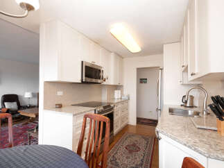 This bright and airy kitchen features sleek white cabinetry, granite countertops, and a modern subway tile backsplash.