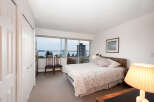 Experience breathtaking water and city views from this serene bedroom, featuring a comfortable queen-size bed with a floral comforter.