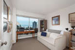 Enjoy stunning water views from this bright living space, featuring a comfortable sofa and a dedicated workspace by the large window.