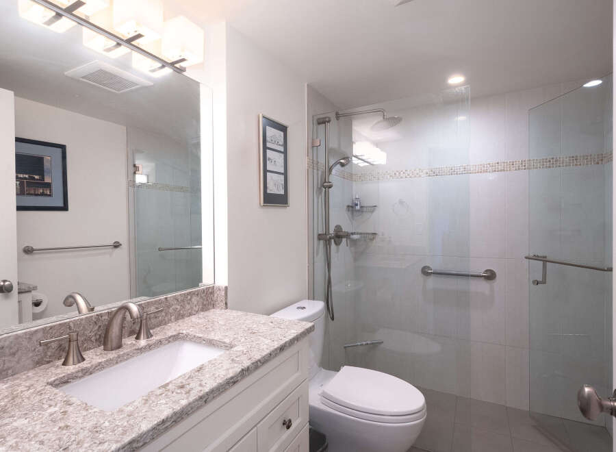 Experience modern comfort in this beautifully appointed bathroom, featuring a spacious walk-in shower with sleek glass doors and convenient grab bars.