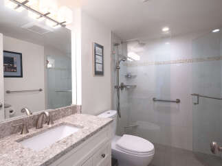 Experience modern comfort in this beautifully appointed bathroom, featuring a spacious walk-in shower with sleek glass doors and convenient grab bars.