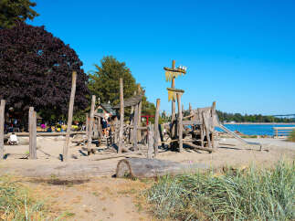 Discover a unique waterfront property featuring a charming, rustic wooden playground perfect for family fun.