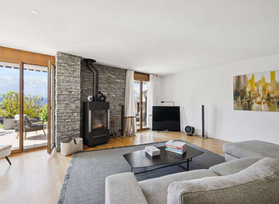 Experience modern living with this stunning living room featuring a sleek wood-burning stove set against a rustic stone accent wall.