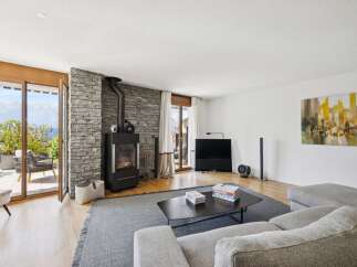 Experience modern living with this stunning living room featuring a sleek wood-burning stove set against a rustic stone accent wall.