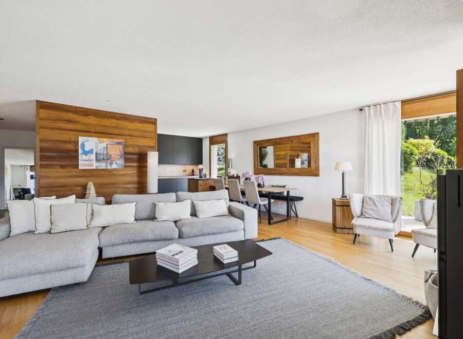 Experience modern living in this spacious open-concept home, featuring a sleek grey sectional sofa and a striking wooden accent wall.