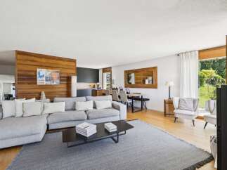 Experience modern living in this spacious open-concept home, featuring a sleek grey sectional sofa and a striking wooden accent wall.