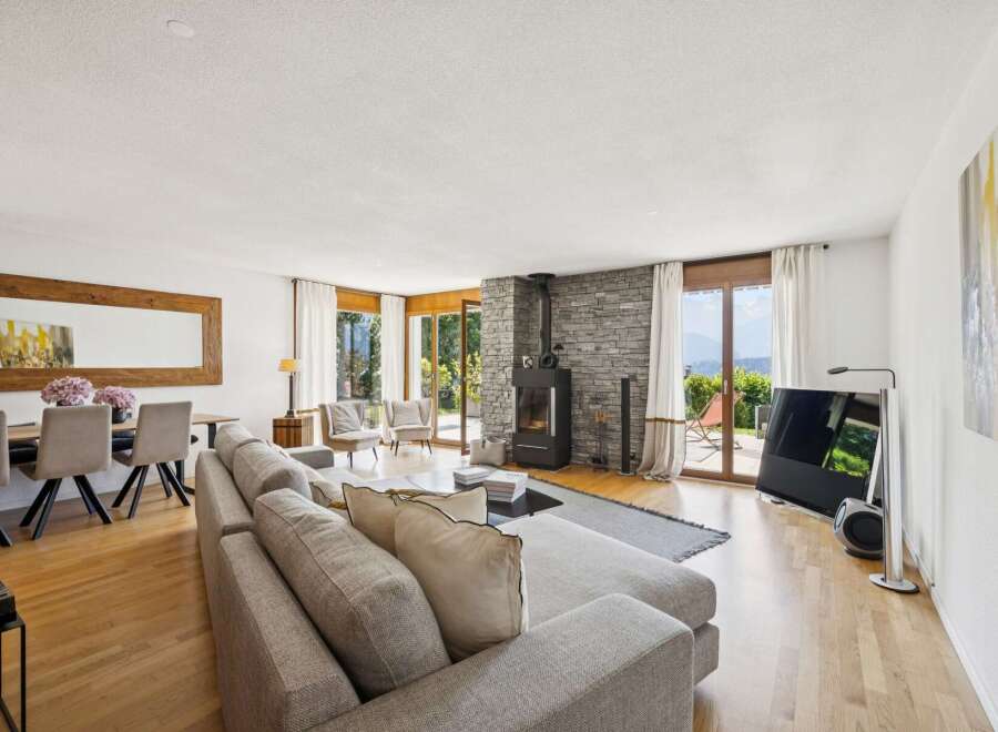 Experience modern living in this spacious open-concept living area, featuring a cozy stone fireplace and large windows that flood the space with natural light.
