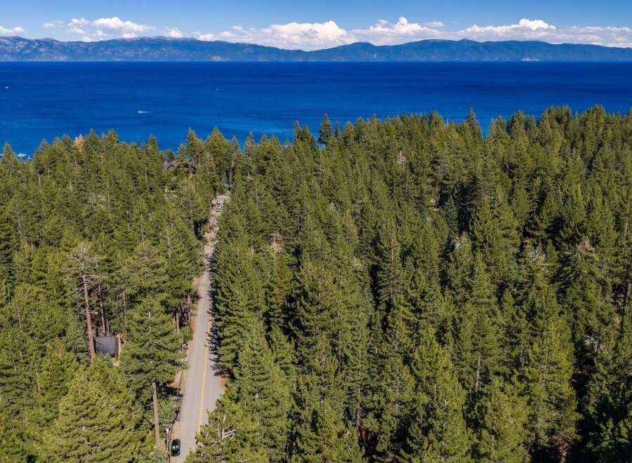 Nestled amidst a dense forest of pine trees, this property offers a serene escape with breathtaking views of a vast, blue lake and distant mountains.