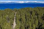 Nestled amidst a dense forest of pine trees, this property offers a serene escape with breathtaking views of a vast, blue lake and distant mountains.