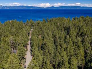 Nestled amidst a dense forest of pine trees, this property offers a serene escape with breathtaking views of a vast, blue lake and distant mountains.