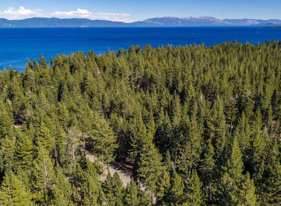 Experience the ultimate mountain lifestyle with this stunning aerial view of a property nestled amidst a dense pine forest.