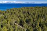 Experience the ultimate mountain lifestyle with this stunning aerial view of a property nestled amidst a dense pine forest.